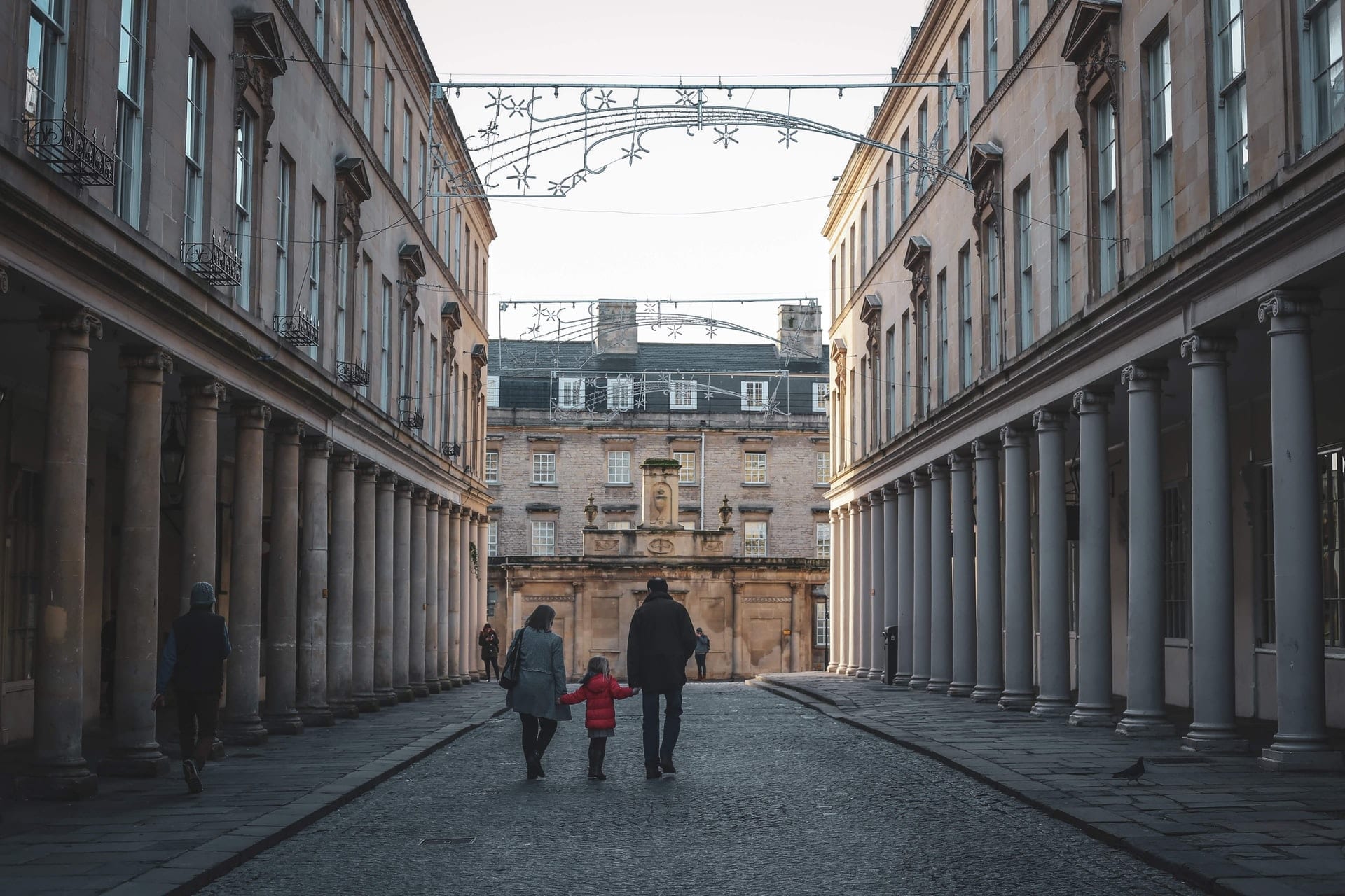 family-walking-down-a-street-in-bath-england-in-december-at-christmas