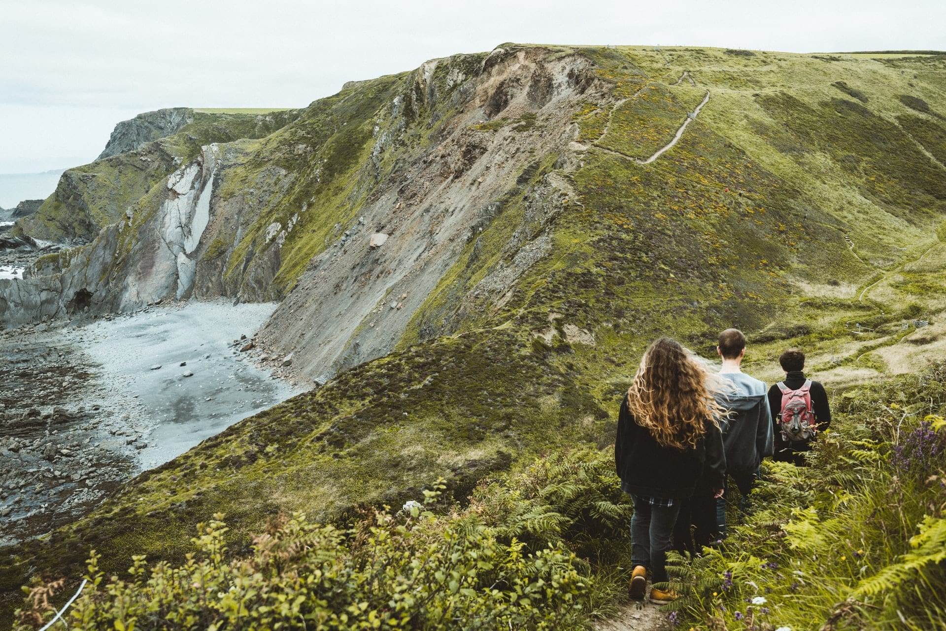 friends-walking-amid-greenery-along-coastal-cliffs-atlantic-highway-cornwall