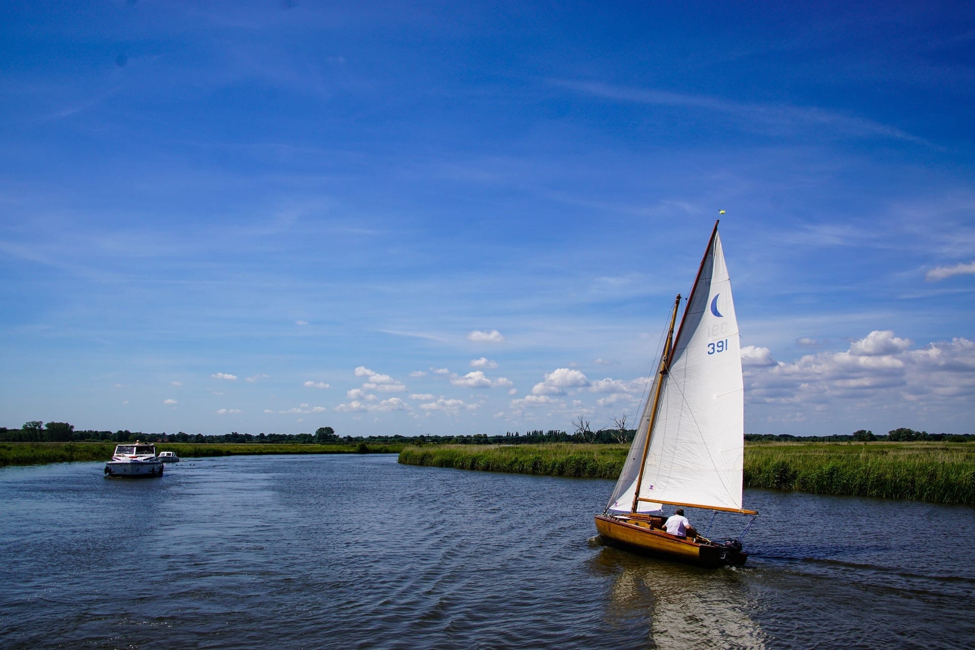 man-in-boat-on-sunny-summer-day-sailing-across-the-norfolk-broads-england