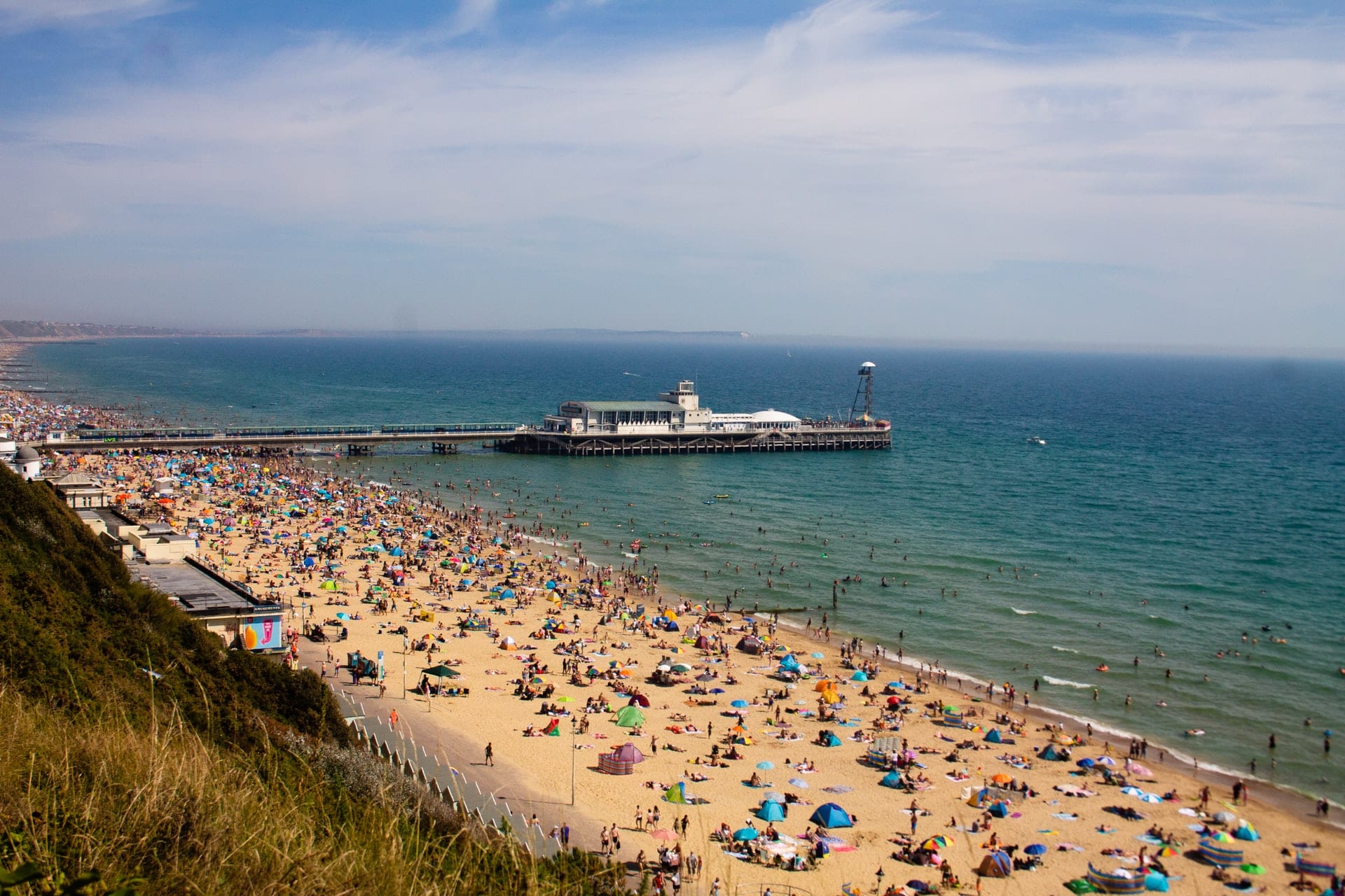 tourists-sunbathing-on-sandy-beach-by-pier-and-sea-in-bournemouth-england