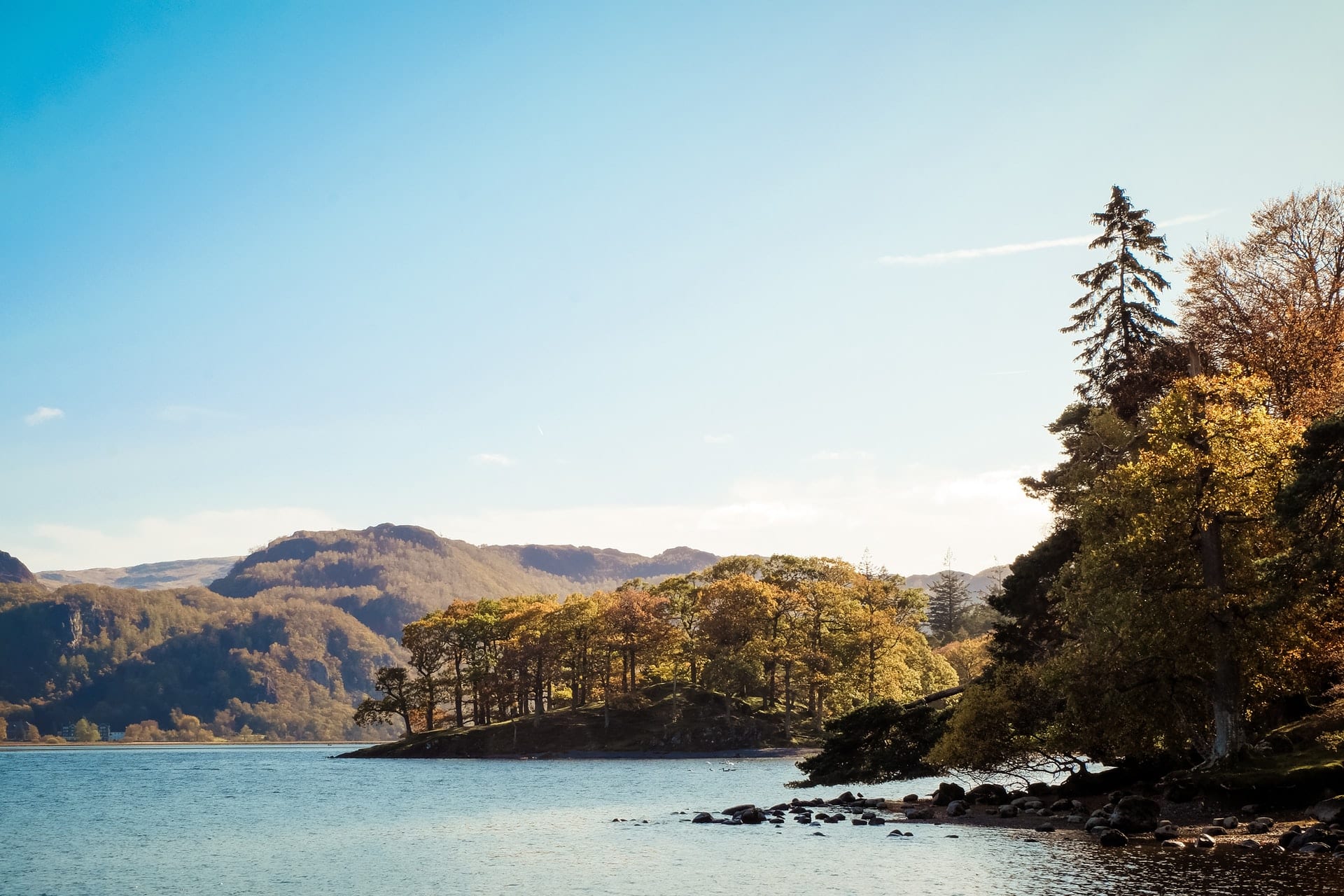 trees-and-mountains-surrounding-lake-with-blue-skies-lake-district-day-trips-from-manchester