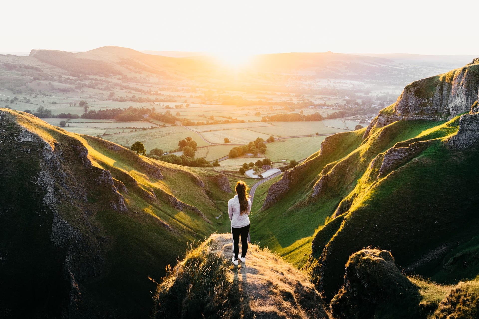 walking-standing-on-rock-overlooking-fields-at-sunset-at-winnats-pass-in-the-peak-district-england-day-trips-from-birmingham